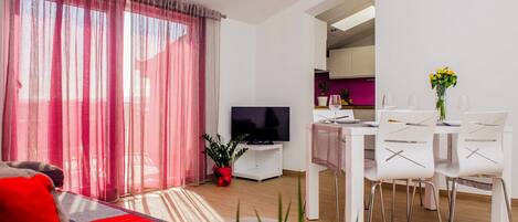 Una sala de estar moderna con sofá, televisión, mesa de comedor y sillas.