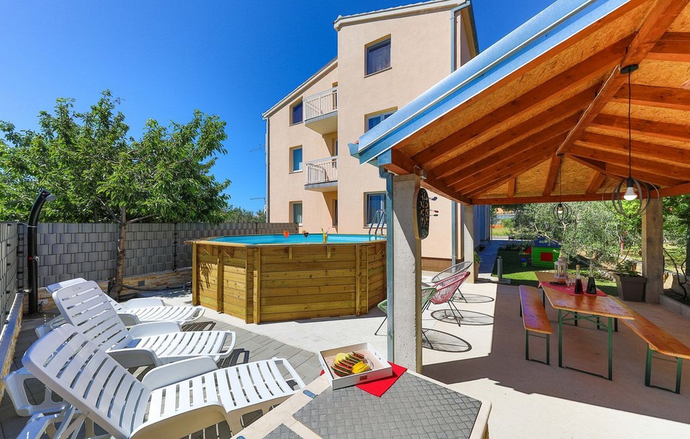 Un área de piscina con sillones de descanso, un jacuzzi y una zona de estar techada.