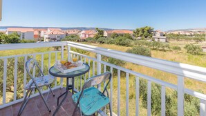 Ein Balkon mit Tisch und Stühlen, der auf einen Wohnbereich mit Häusern und Grünflächen blickt.
