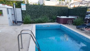 A rectangular swimming pool with a tiled edge, a metal ladder, and lounge chairs. - Kastel Stafilic Comfortable Apartments (Kastela)