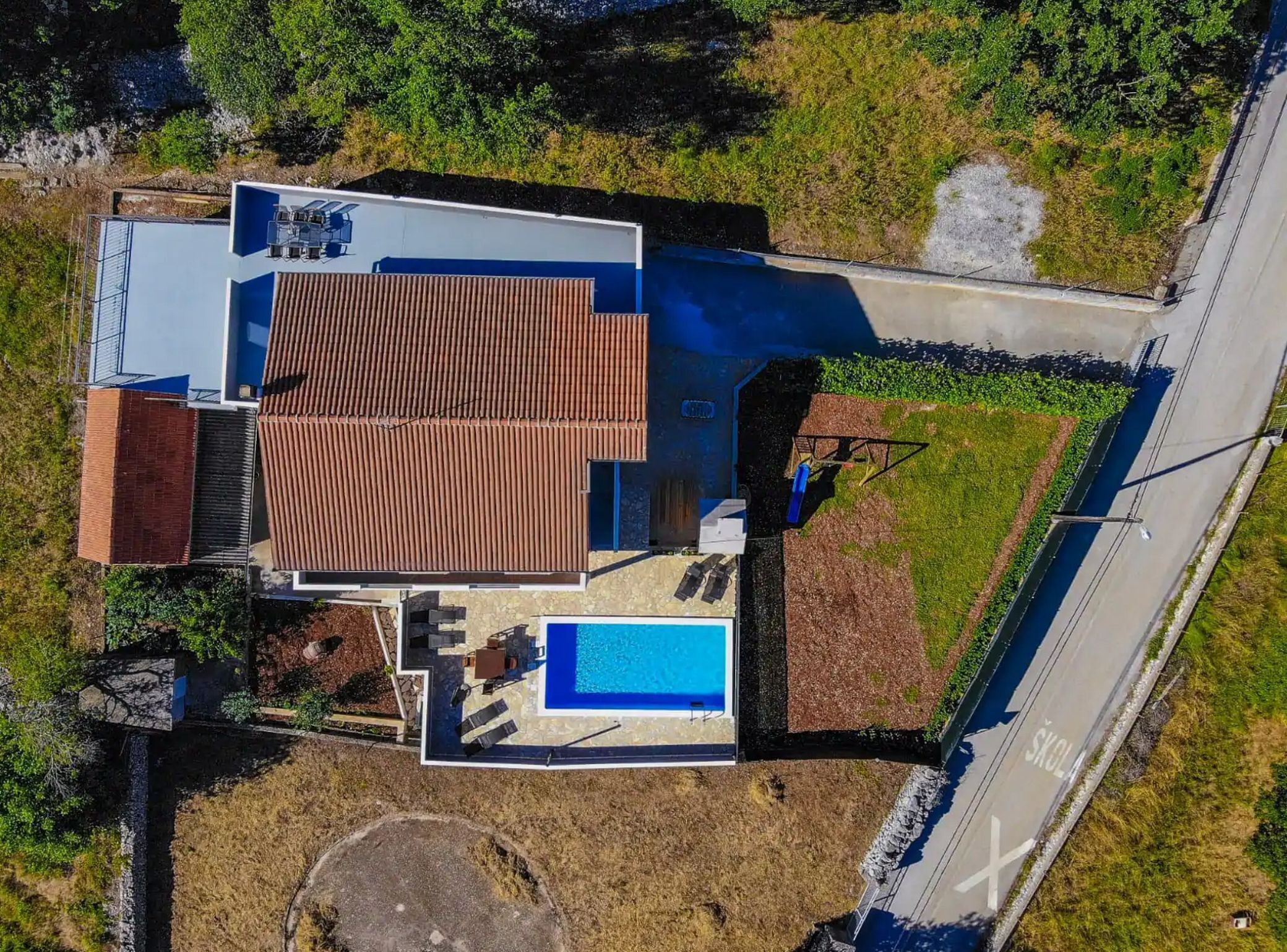 A modern house with a swimming pool, a covered patio, and a large garden.