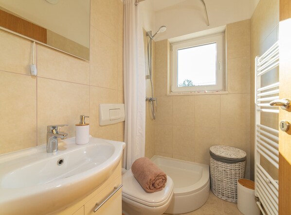 Une salle de bain équipée d’un lavabo, de toilettes, d’une douche et d’une fenêtre.