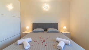 A neatly made bed with two pillows, two bedside lamps, and a decorative light fixture above the bed. - Idyllic Getaway Lovrec Villa With Pool (Lovrec)