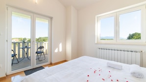 A bedroom with a large bed, a view of the outdoors through a sliding door, and a window with a view of the landscape. - Idyllic Getaway Lovrec Villa With Pool (Lovrec)