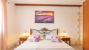 A bedroom with a bed, two nightstands, a wall-mounted painting, and a stone accent wall. - Serene Retreat Holiday Home With Pool (Klis)