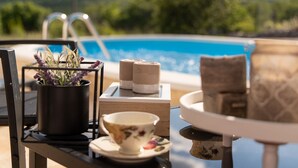 A poolside table with a potted plant, candles, a teacup, and a view of a swimming pool and mountains. - Serene Retreat Holiday Home With Pool (Klis)