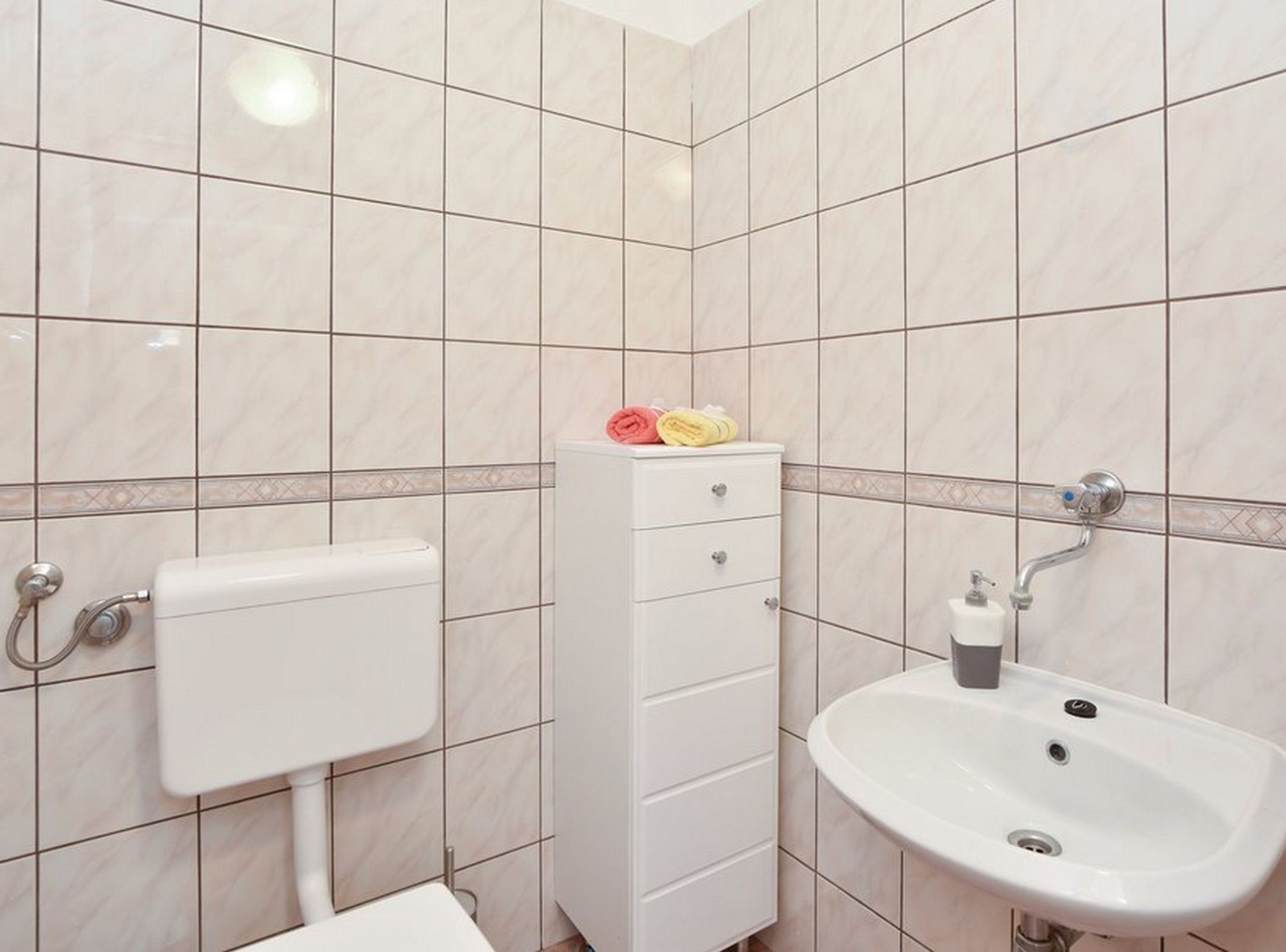 A bathroom with a toilet, a sink, and a cabinet.