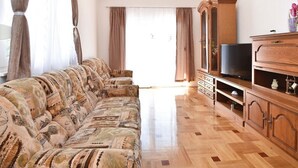 Un salon avec un canapé à motifs, un meuble en bois et un téléviseur.