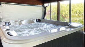 A hot tub with a wooden deck and a view of a lake and trees. - 4 Star Holiday Home in Ljusfallshammar (Ljusfallshammar)