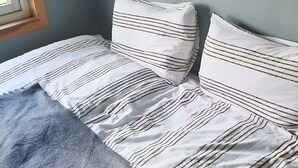 Uma cama com roupa de cama listrada e um cobertor azul.