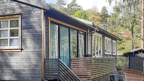 Uma cabana de madeira com varanda coberta e escada para um alpendre.
