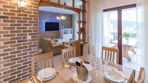 Un coin repas avec un mur en briques, un téléviseur fixé au mur et un balcon avec vue.