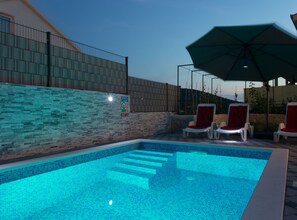 A swimming pool with tiled steps leading into it, surrounded by lounge chairs and an umbrella. - Elegant Oasis Vinisce Villa With Pool (Marina)