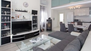 Ein modernes Wohnzimmer mit einem großen Flachbildfernseher, einem Glastisch und einem grauen Sofa.