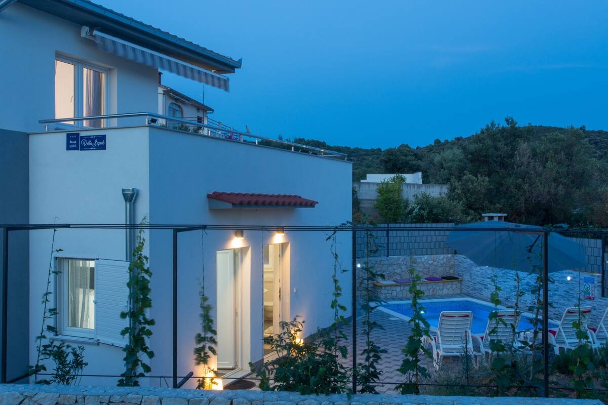 Una villa moderna con piscina, un espacio exterior cubierto y vistas del paisaje circundante.