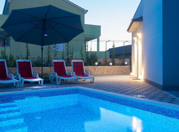 Una piscina al aire libre de temporada, sillones reclinables de piscina