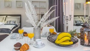 Un plateau de petit-déjeuner avec une variété d’aliments, notamment des bananes, des muffins et du jus d’orange, est disposé sur une table blanche dans une chambre d’hôtel.