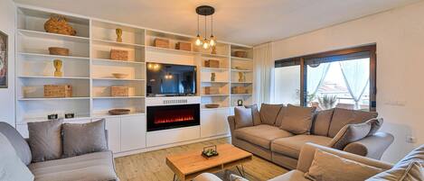 Una sala de estar moderna con chimenea, estanterías empotradas y un televisor grande.