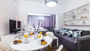 Un salon moderne avec une table à manger dressée pour le petit-déjeuner, un canapé et un téléviseur.