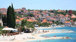 Una cittadina costiera con una spiaggia, edifici dai tetti rossi e un mare cristallino.