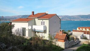 Une maison située sur la côte, avec un toit recouvert de tuiles rouges, une antenne parabolique et une vue sur la mer.