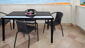 Un balcon avec une table et des chaises, donnant sur une étendue d’eau et sur des collines lointaines.