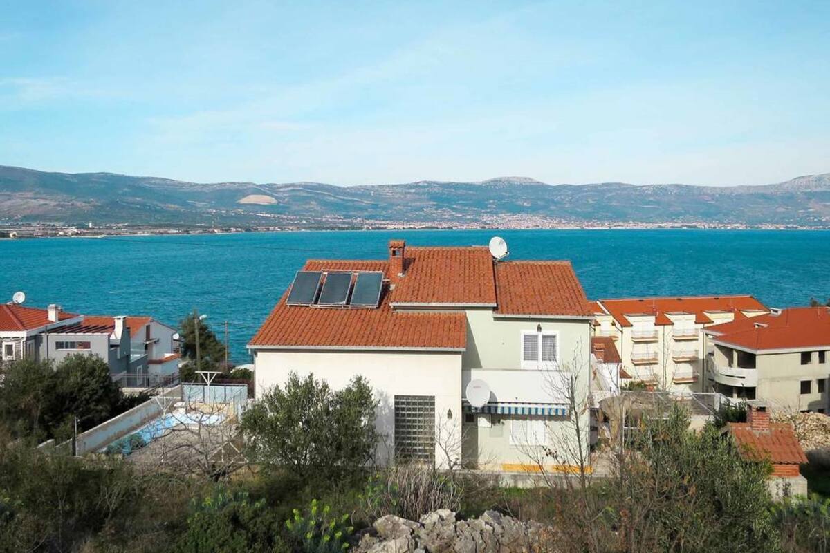 A coastal residential area with houses featuring red-tiled roofs and solar panels.