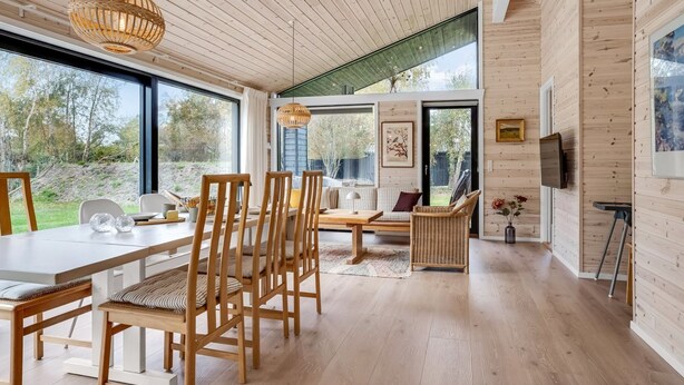 A modern interior with wooden floors, a dining area with chairs and a table, a sofa, and a television on the wall. - "Aruna" - 550m from the sea by Interhome (Idestrup)