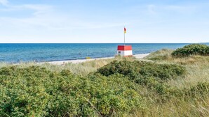 A beach with a small red and white structure, likely a lifeguard station, near the water. - "Aruna" - 550m from the sea by Interhome (Idestrup)