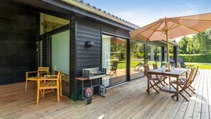 A wooden deck with outdoor furniture, a grill, and a large umbrella. - "Aruna" - 550m from the sea by Interhome (Idestrup)