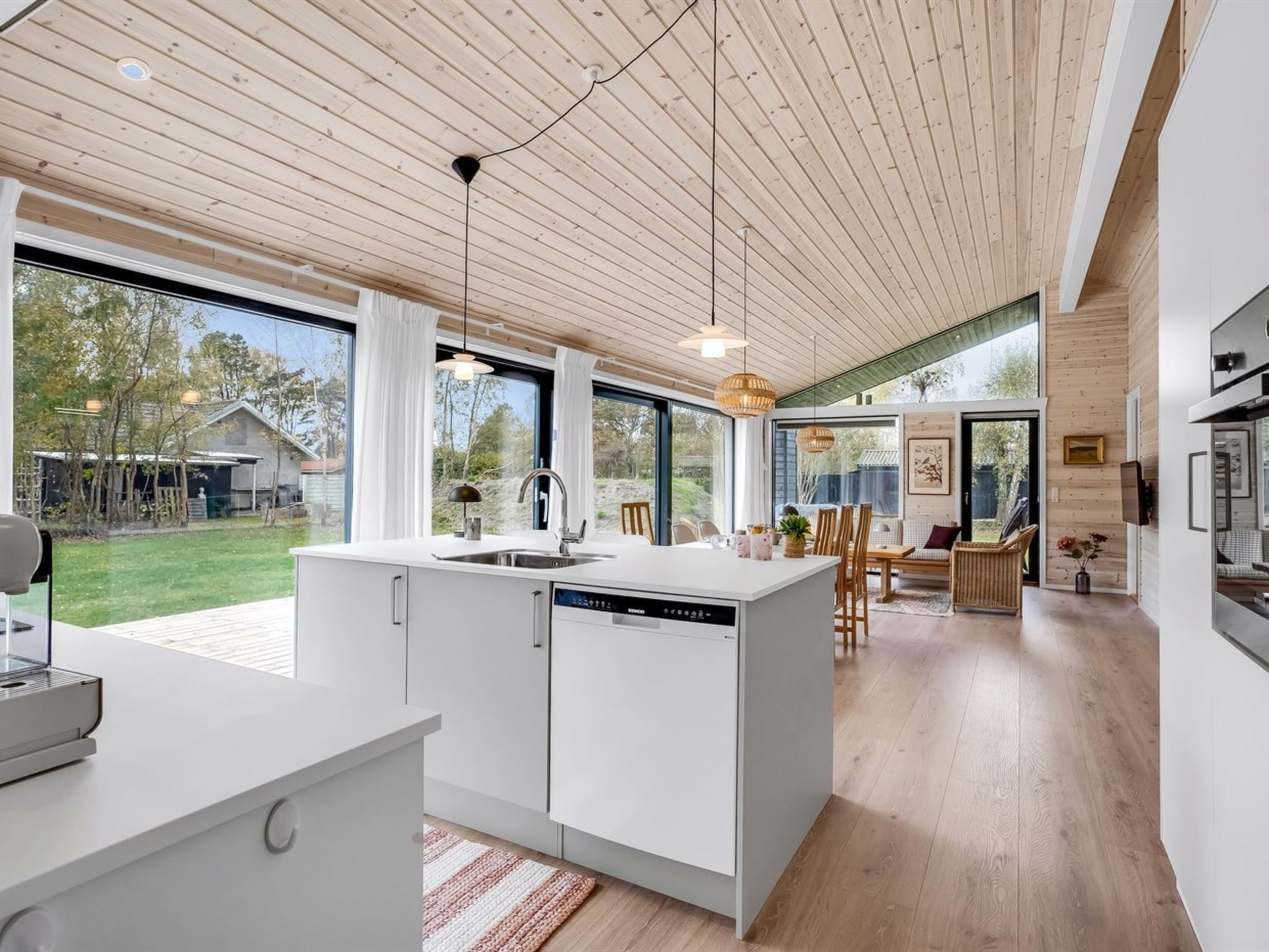 A modern kitchen with a large island, a dining area with a view, and a living space with a fireplace.