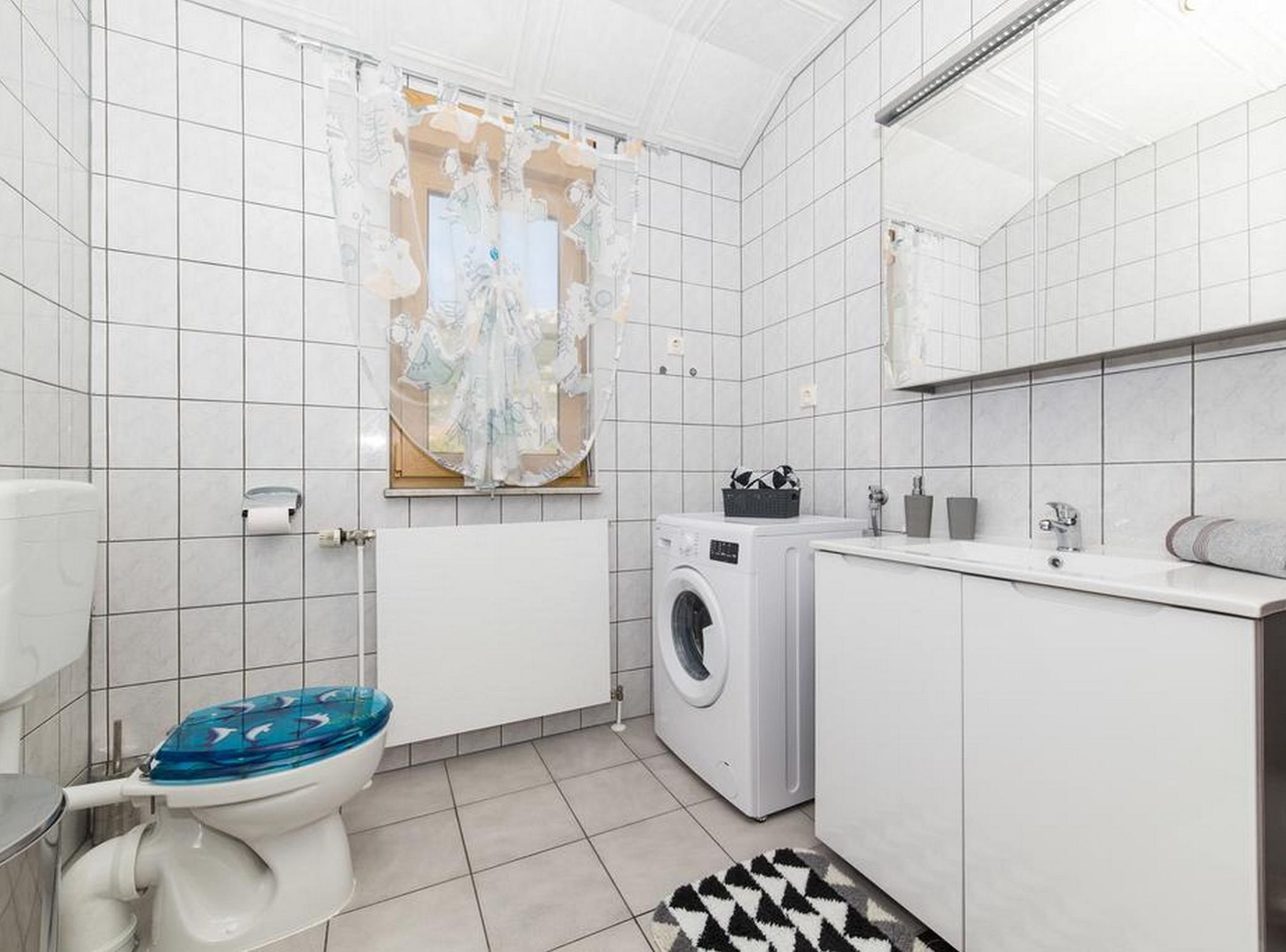 A modern bathroom with a toilet, washing machine, and sink.