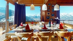 A wooden interior with a table set for dining, large windows with a mountain view, and hanging pendant lights. - Mont Bijou Mountain & Quiet Chalet 10 Pers (Veysonnaz)