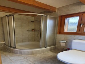 Un baño con cabina de ducha, inodoro y ventana.