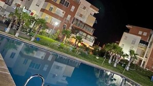 A nighttime view of a residential building complex with a swimming pool. - Magnificent apartment with green spaces 2 minutes walk from Houara-Tanger beach (Tanger)