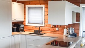Eine moderne Küche mit weißen Schränken, einem eingebauten Herd und einem Fenster mit Jalousien.