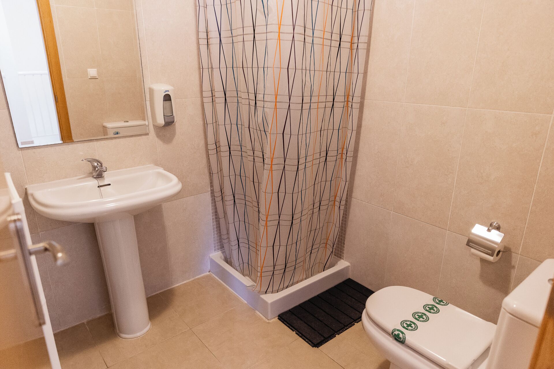 Une salle de bain avec un lavabo, des toilettes et un rideau de douche.