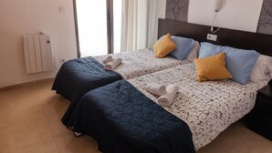 A double bed with patterned bedding and two pillows, a bedside table, and a wall-mounted light fixture. - Apartamentos LA PARRETA CENTRO (Vinaros)