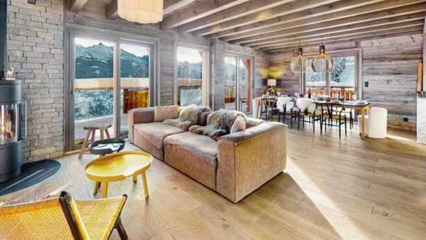 A spacious living area with a wooden ceiling, a fireplace, a sofa, and a dining area with a table and chairs. - Chalet With Garden and Mountain View (Vex)