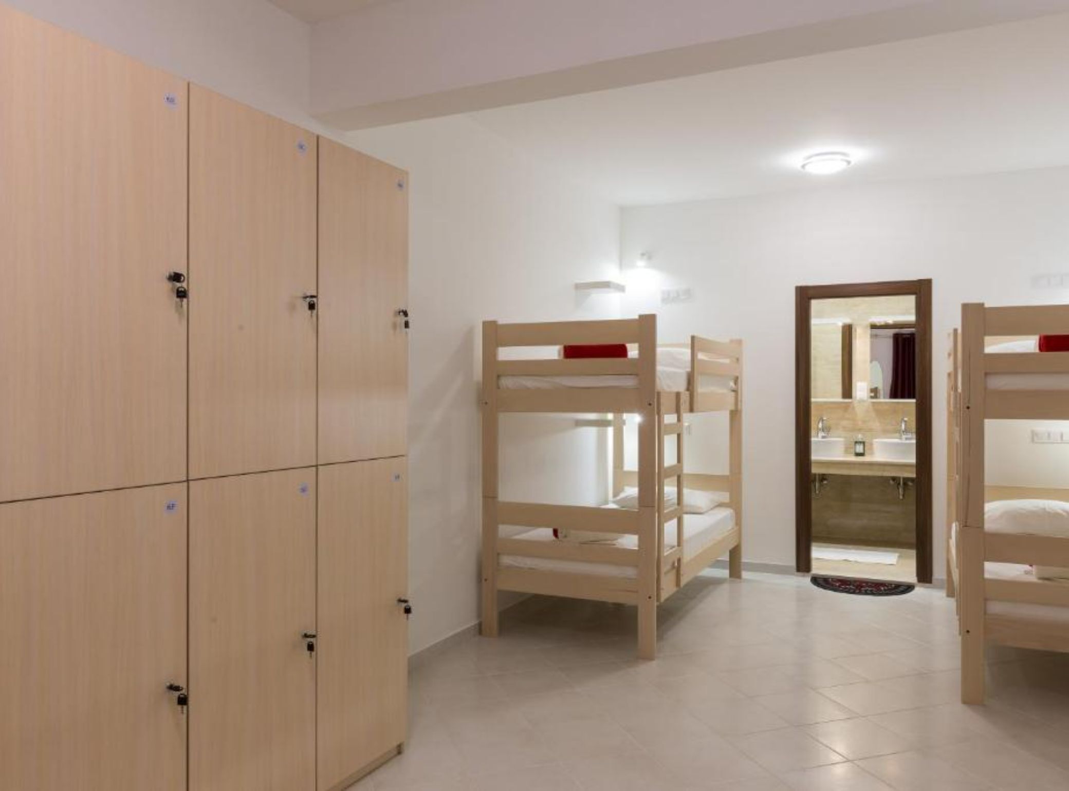 Una habitación con literas, un armario de madera y un baño con espejo y lavamanos.