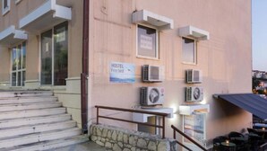 A hostel with a stone staircase, outdoor seating, and air conditioning units on the exterior wall. - Hostel Free Bird (Dubrovnik)