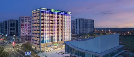 A Holiday Inn Express hotel with a modern glass facade, surrounded by other high-rise buildings.