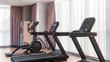 Un gimnasio moderno con dos cintas de correr, una bicicleta estática y un banco para pesas.