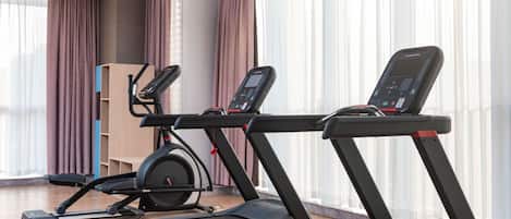 A modern gym with two treadmills, a stationary bike, and a weight bench.