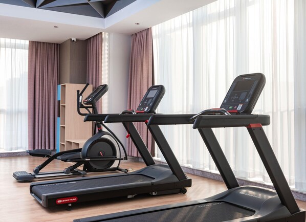 Un gimnasio moderno con dos cintas de correr, una bicicleta estática y un banco para pesas.