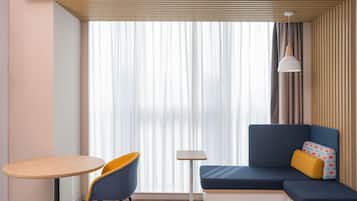 Una habitación moderna con un sofá, una mesita redonda y una silla.