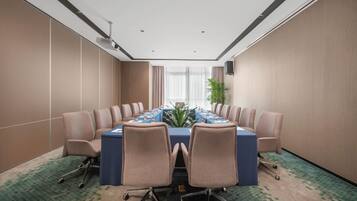 Une salle de conférence équipée d’une longue table, de chaises et d’un projecteur.