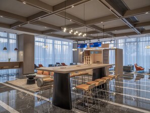 Un interior moderno con una isla central, zona de estar y ventanas amplias.