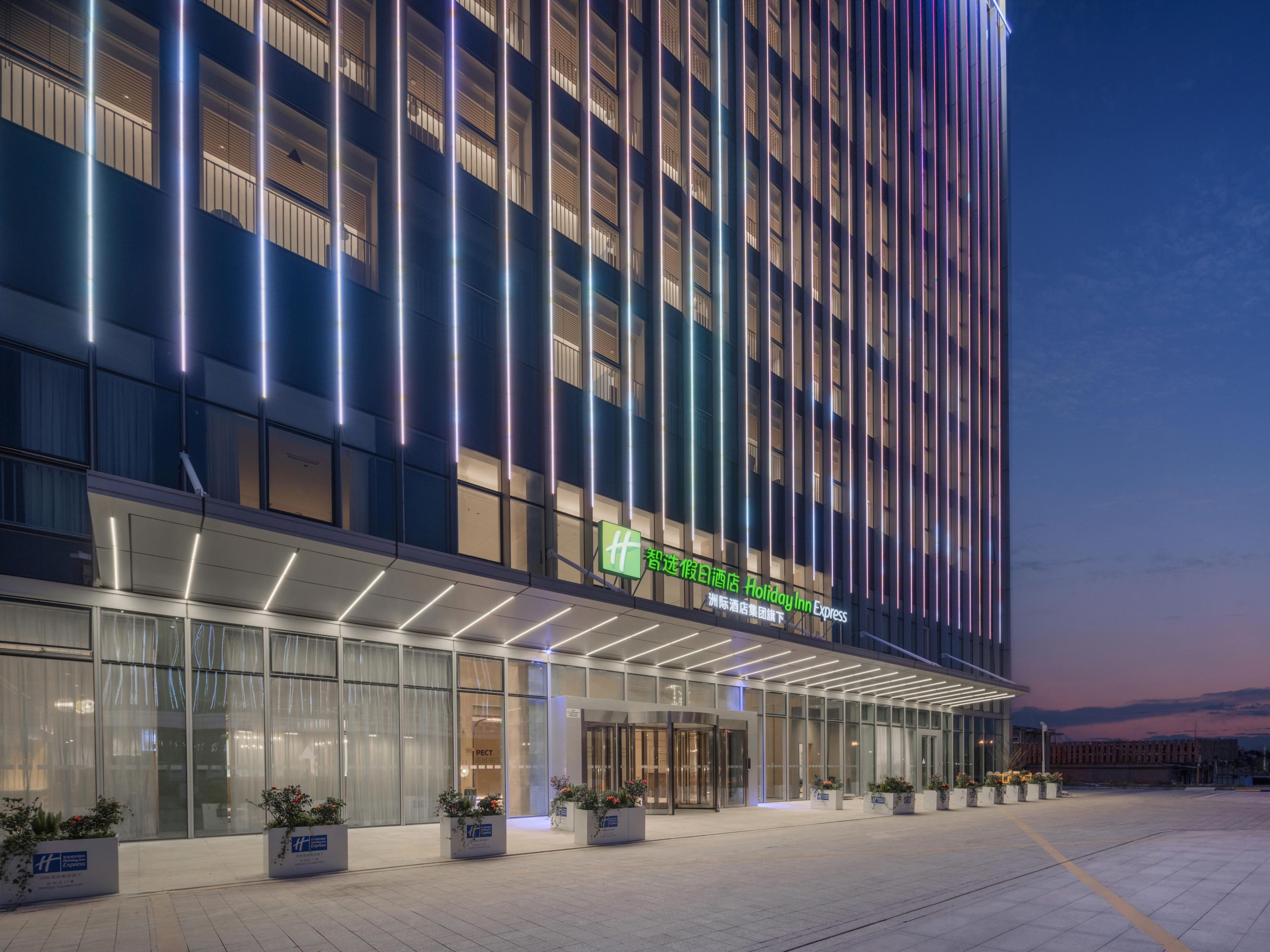 A modern hotel with a prominent entrance, large windows, and a well-lit facade.