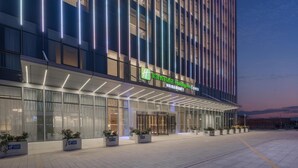 A modern hotel with a prominent entrance, large windows, and a well-lit facade. - Holiday Inn Express Taizhou Toumen Port (Taizhou)